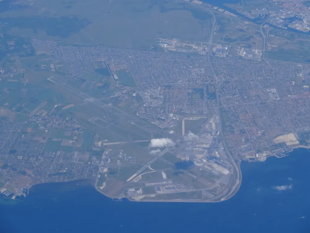 Copenhagen Kastrup Airport seen from high altitude, its runways on the coast beside the sea