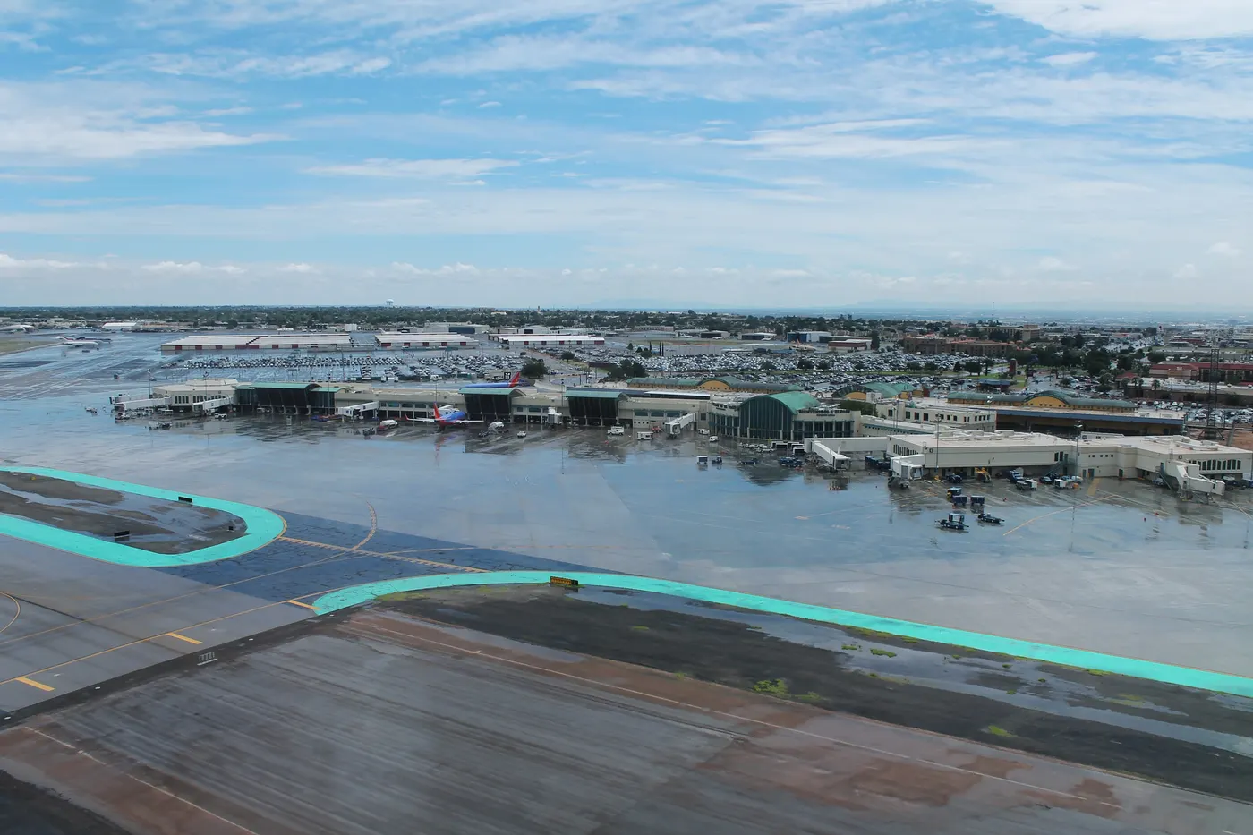El Paso International Airport seen from the air, with terminal buildings, taxiways and the city beyond under a partly cloudy sky