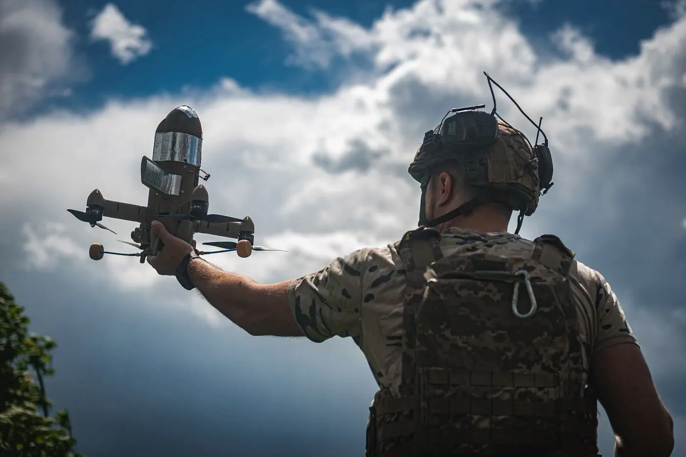 A Ukrainian soldier holds a Sting interceptor drone up against a cloudy sky, ready to launch it