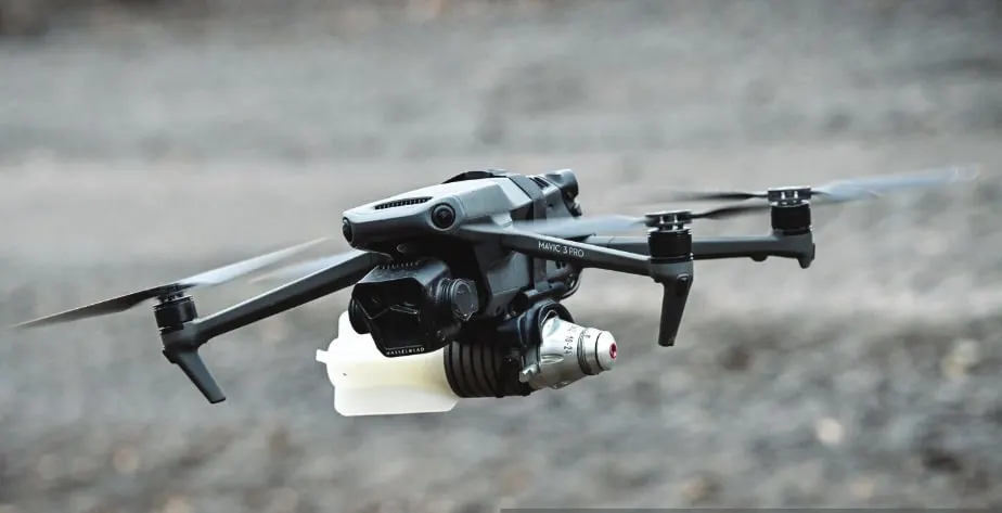 A quadcopter in flight with a small munition clamped beneath it