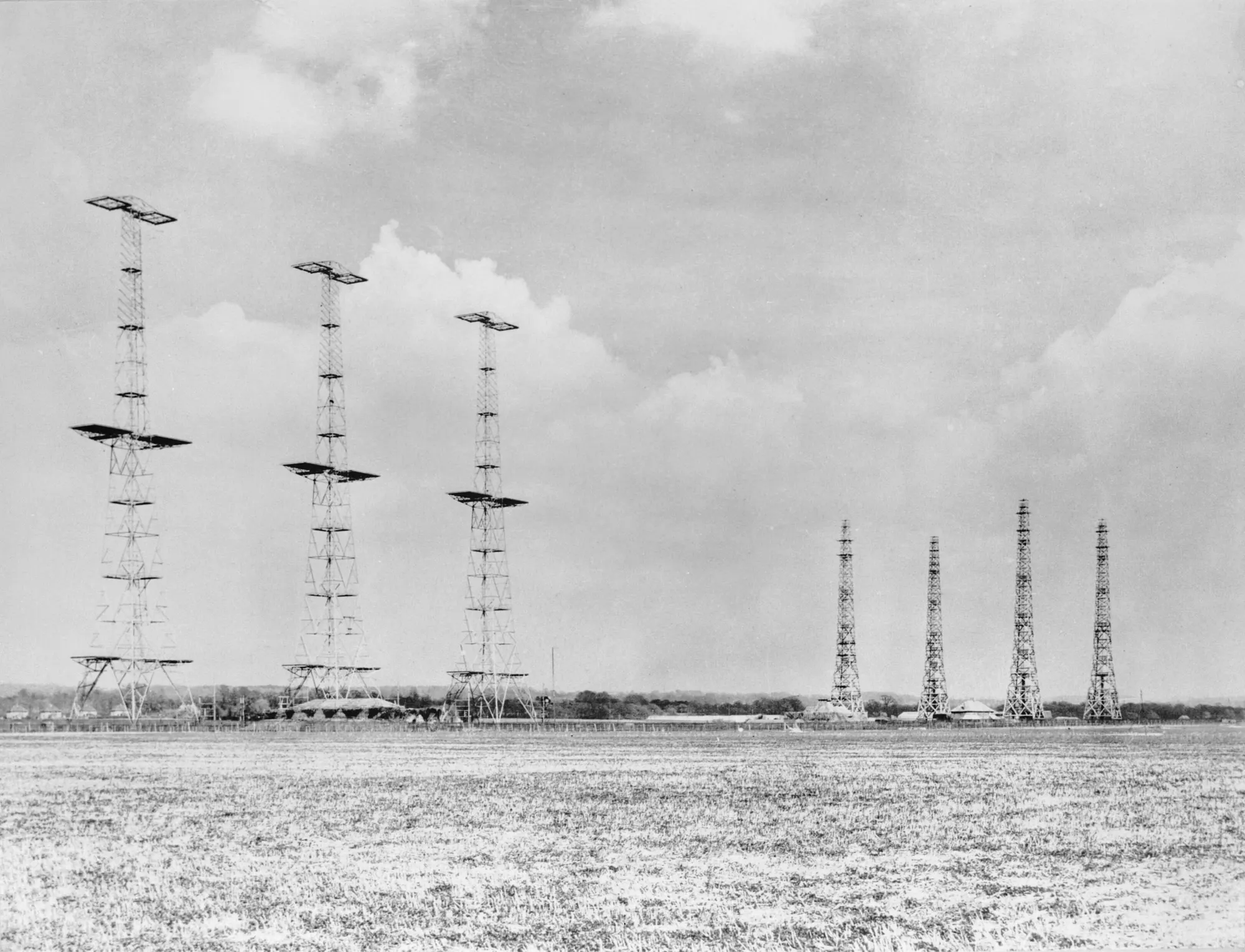 Black-and-white photo of the Chain Home radar station at Poling, Sussex, in 1945, with tall steel transmitter towers and wooden receiver towers on open ground