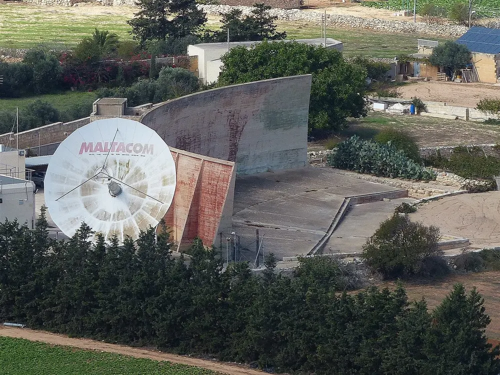 Il-Widna, a long curved concrete acoustic wall in Malta, next to a modern satellite dish