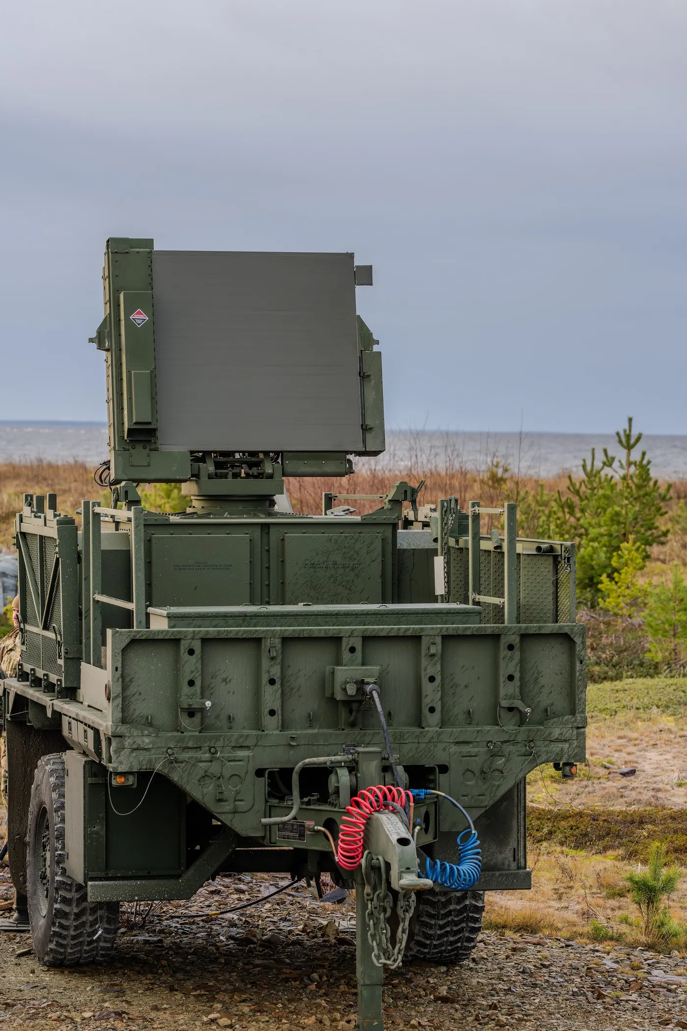 A U.S. Army Sentinel radar on a trailer raised on a small rise of sandy, scrub-covered ground on a grey day in Finland