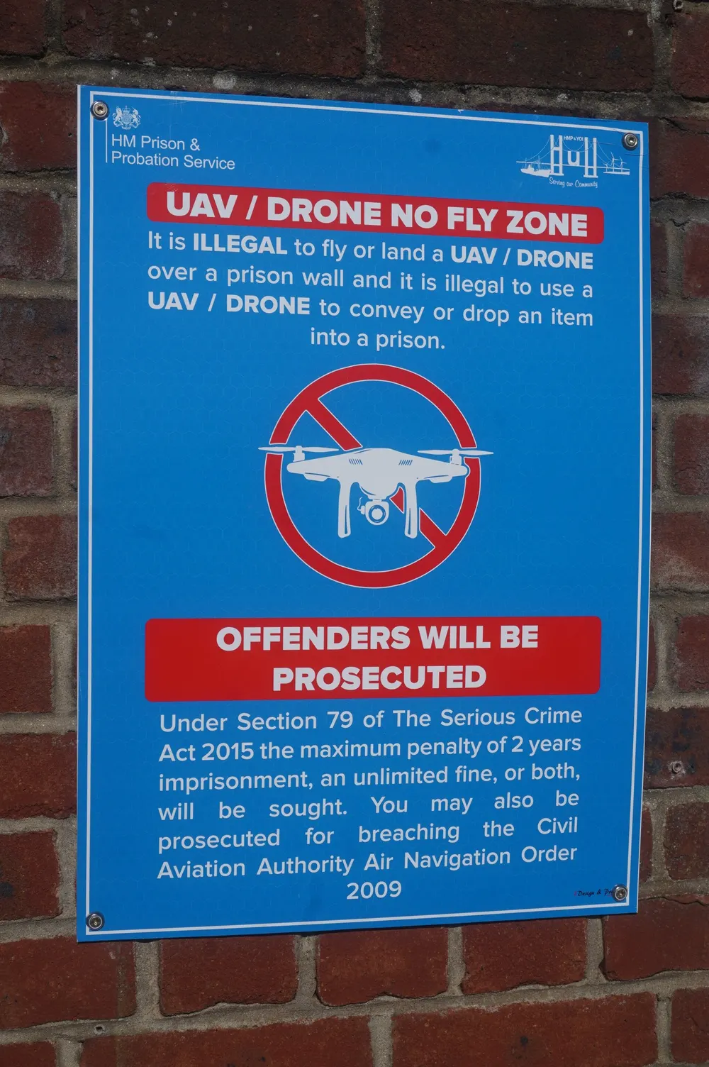 A blue HM Prison and Probation Service sign on a brick wall at HMP Hull reading UAV / drone no fly zone, offenders will be prosecuted