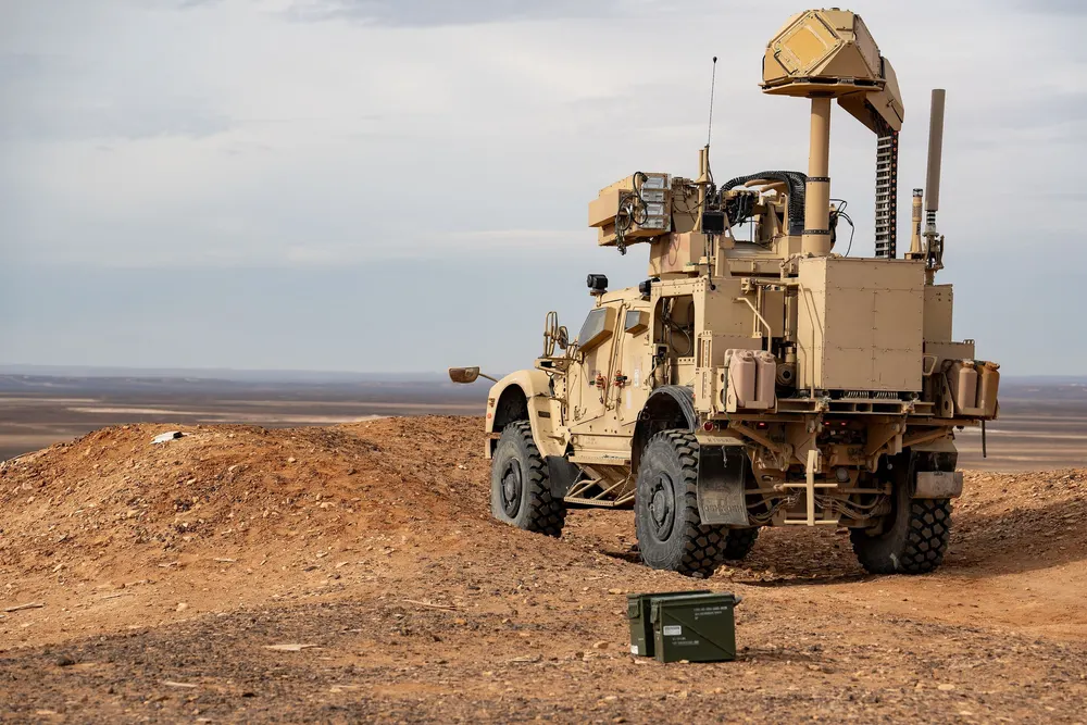 A tan U.S. Air Force M-LIDS vehicle on a raised dirt firing range under a pale sky