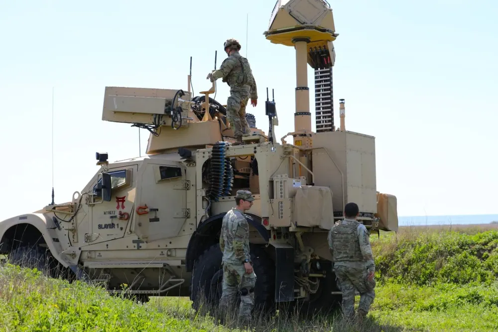 A U.S. Army M-LIDS counter-drone vehicle with its radar and sensor mast during a live-fire exercise in Romania, with soldiers standing beside it